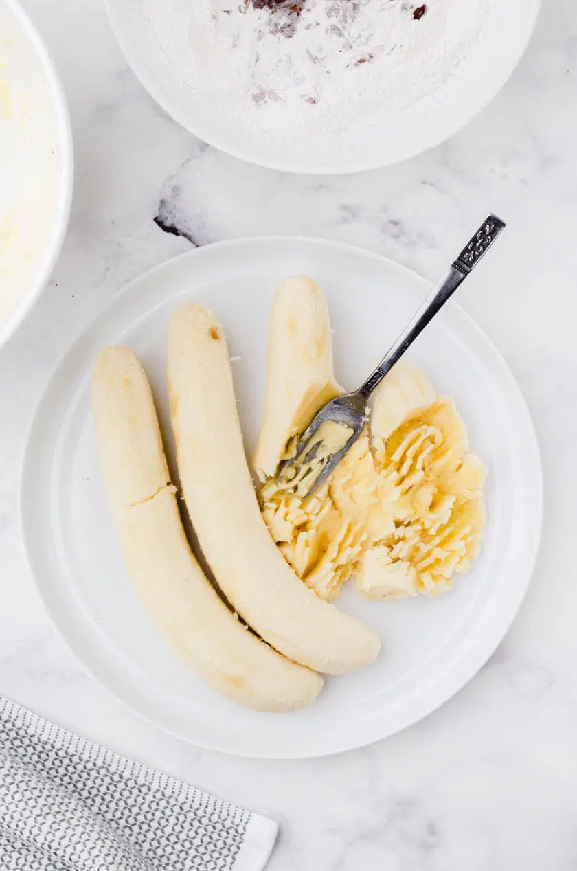 Mash bananas on a plate with a fork.