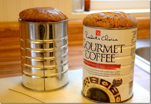 Steamed pudding in coffee cans once it is steamed and finished cooking. It has risen over the top of the cans.