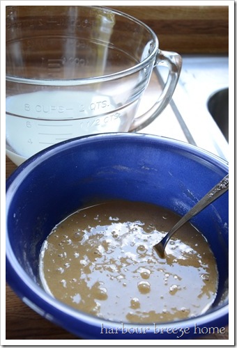 vanilla pudding ingredients stirred together in a mixing bowl with a bowl with milk behind it.