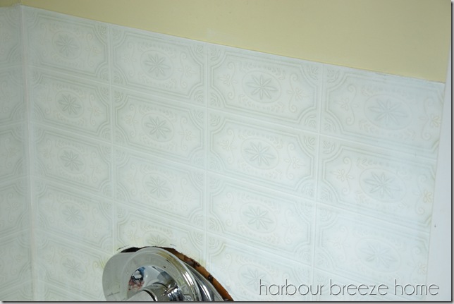 Fake tile board in a bathroom after one coat of primer has been painted on it