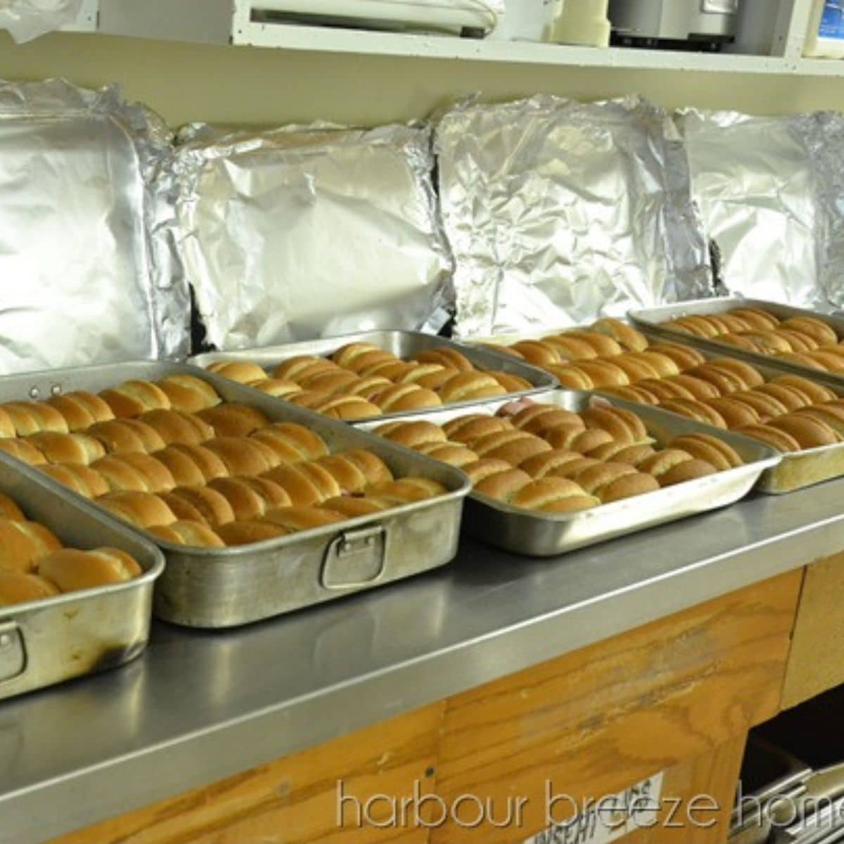 Pans of ham and cheese sliders on counter for 65 people
