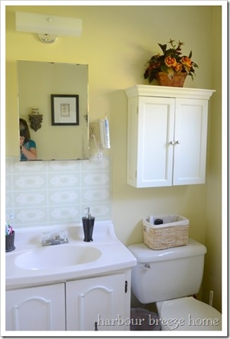 dated bathroom vanity and tile above it with an old fashioned medicine cabinet for a mirror