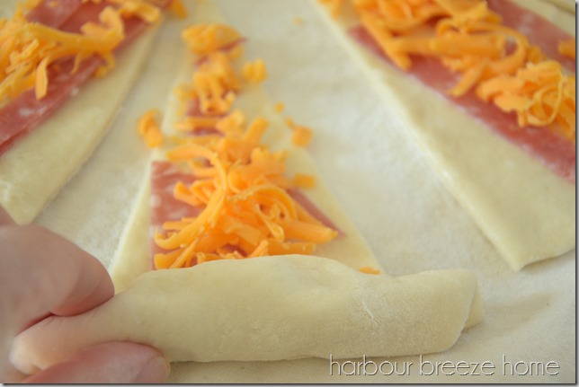Ham and cheese crescent rolls being rolled up.