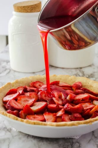 strawberry pie glaze being poured onto strawberry pie.