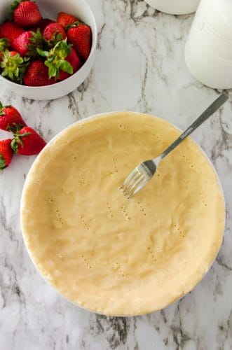 pie crust being pricked with a fork
