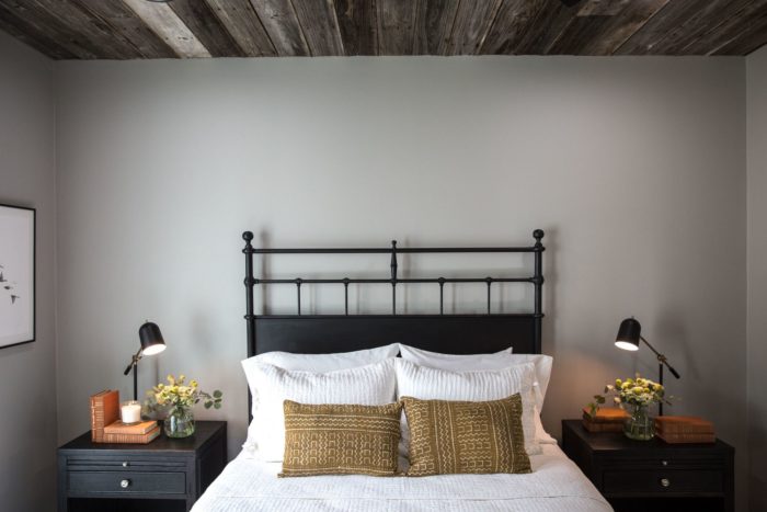 A black iron headboard that is tall behind a bed made with white linens