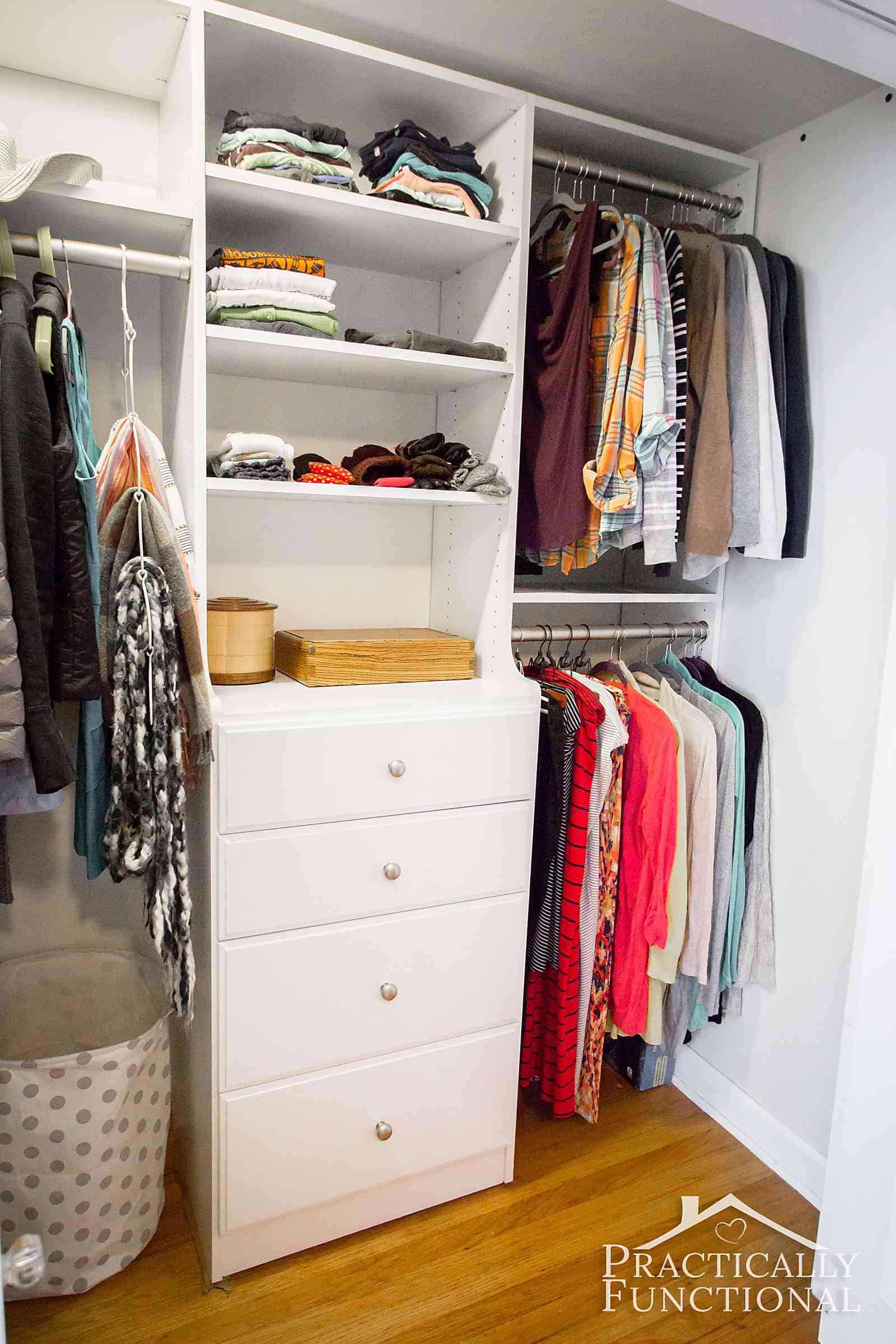 Small closet organization system with hanging clothes on the left and right and a chest of drawers with shelves above in the center.