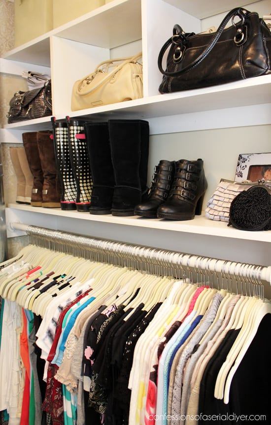 Small closet organization with hanging clothes below and shelves above for shoes and purses.