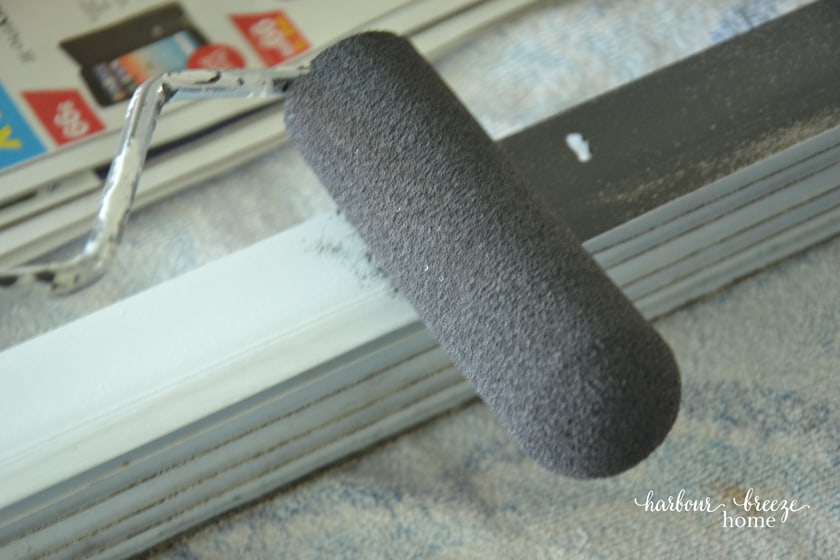 a foam roller painting a dark gray color on a vinyl door sweep