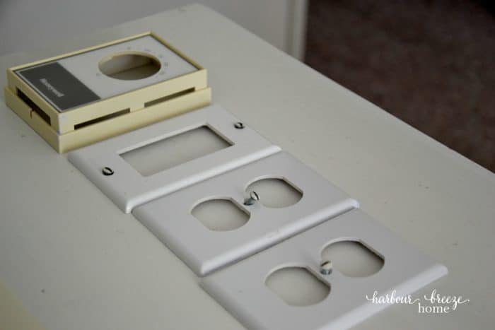Light switch covers and screws lined up on a shelf