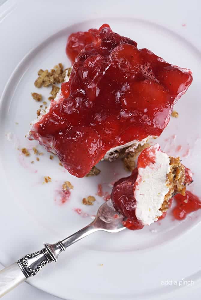 Piece of Strawberry Pretzel salad with a bite cut out of it on a white plate