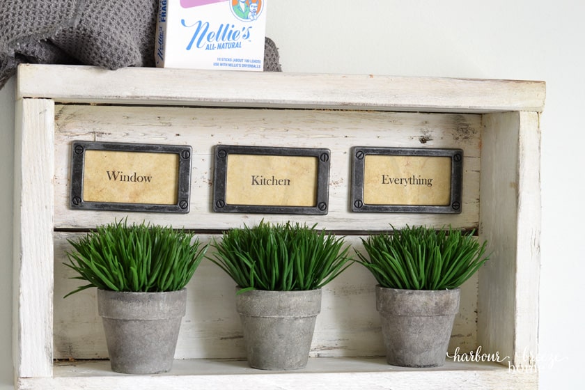 Rustic wall shelf  with hooks with 3 plants in it.