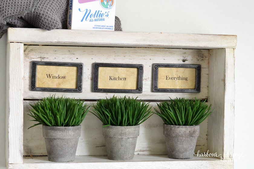 Rustic wall shelf with hooks with 3 plants in it.
