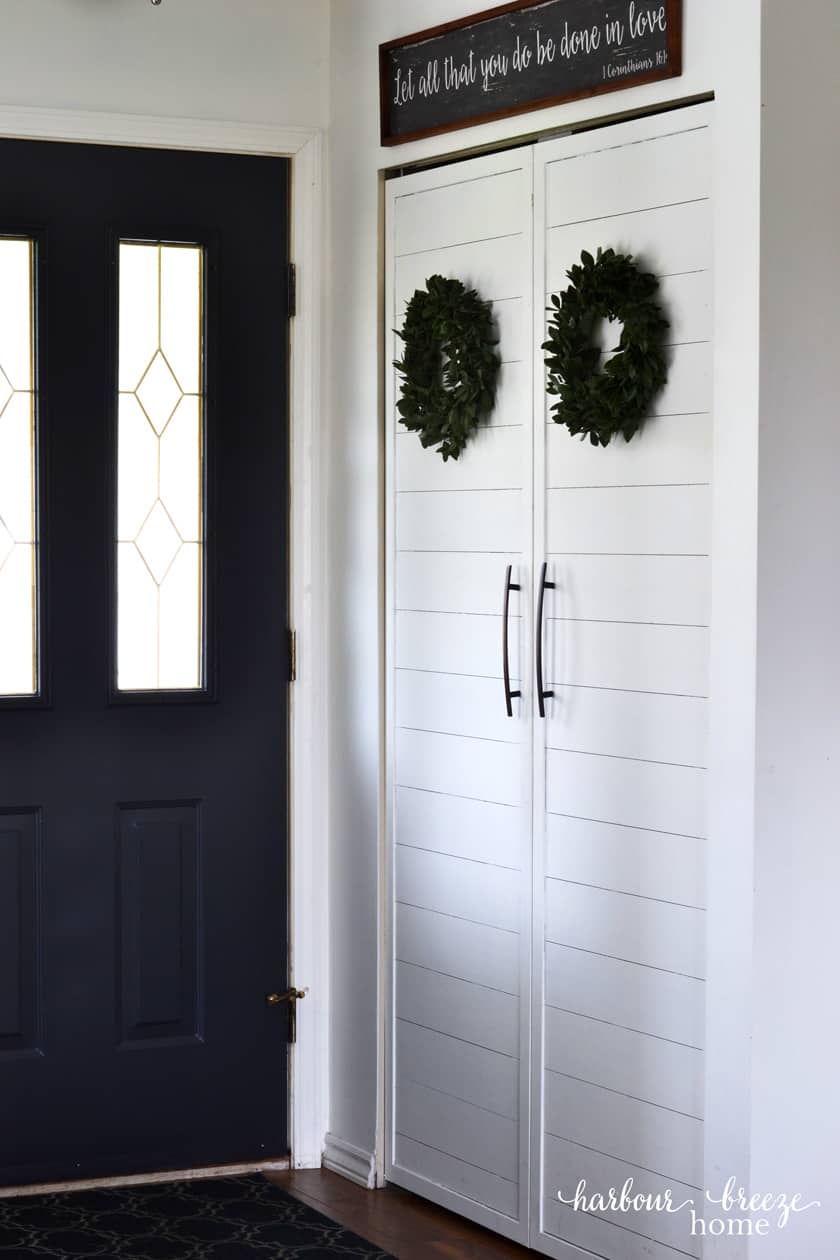 Photo of an entryway closet with boxwood wreaths hanging on it.