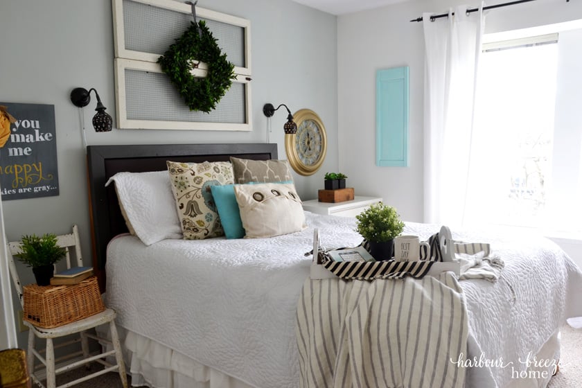 an organized master bedroom with neatly made bed and a tray with a cup of coffee sitting on it.