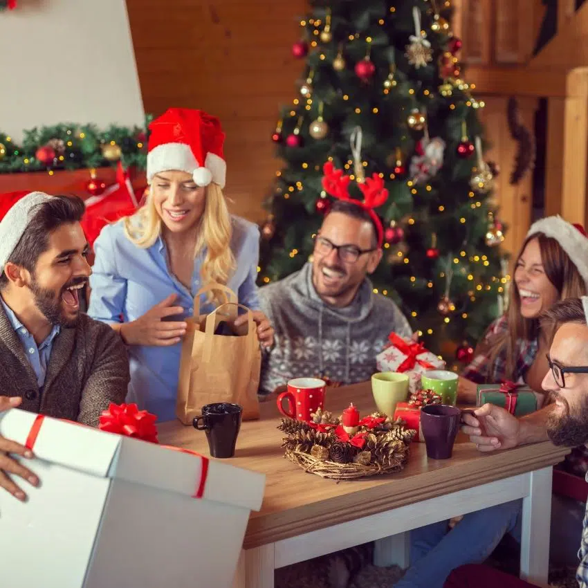 A group of adults sitting around a table playing gift exchange games.