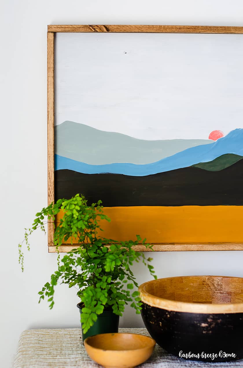 a boho landscape painting of a mountain scene with a simple wood frame around it