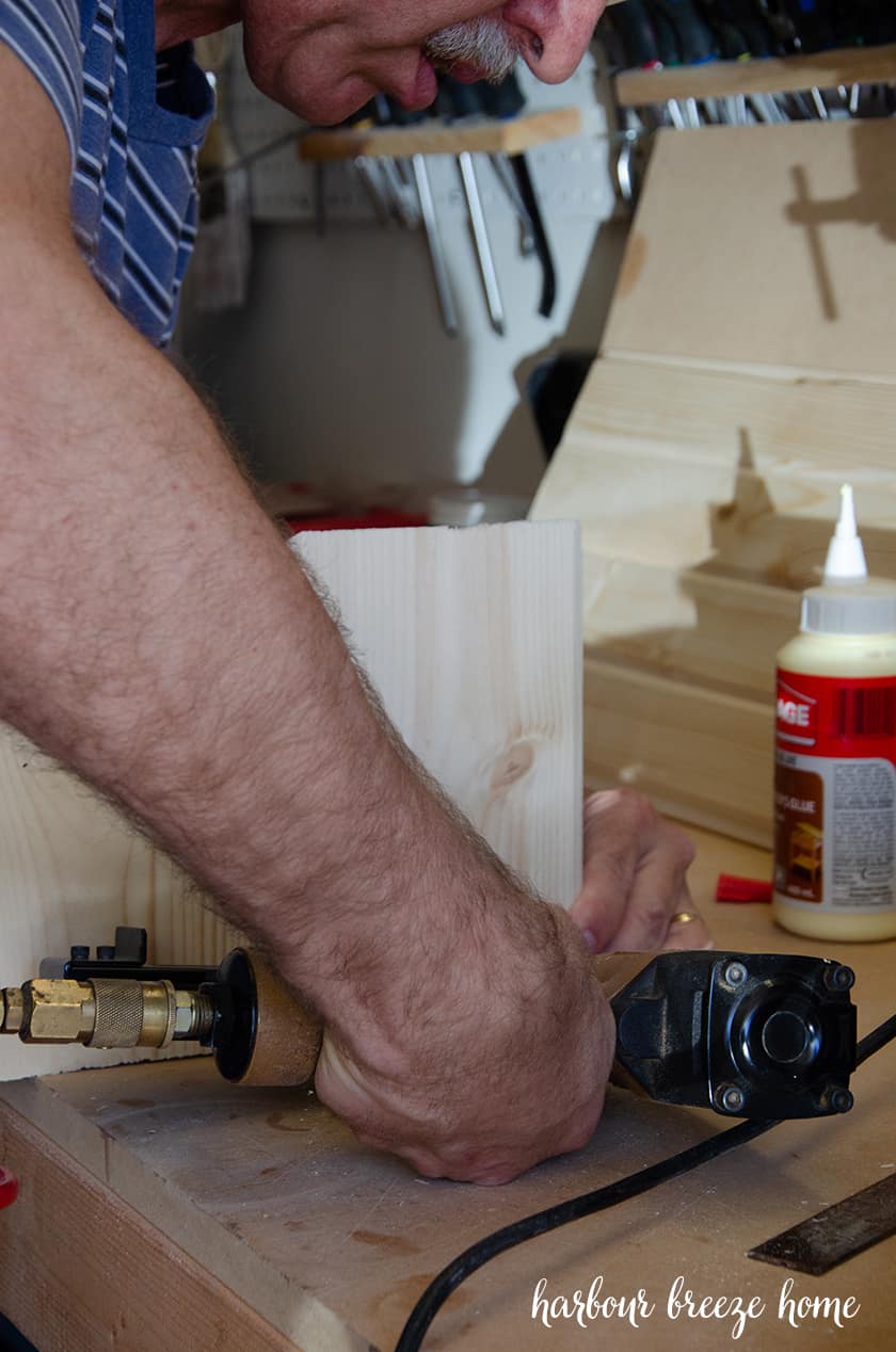 A brad nailer being used to secure the joints of a floating bedside table