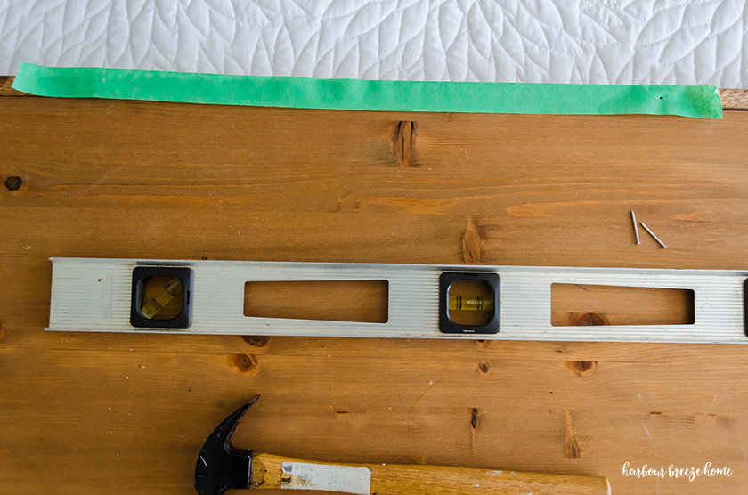 Painters tape laid across the top of a picture with 2 holes in the spot where the hangers need to be placed.