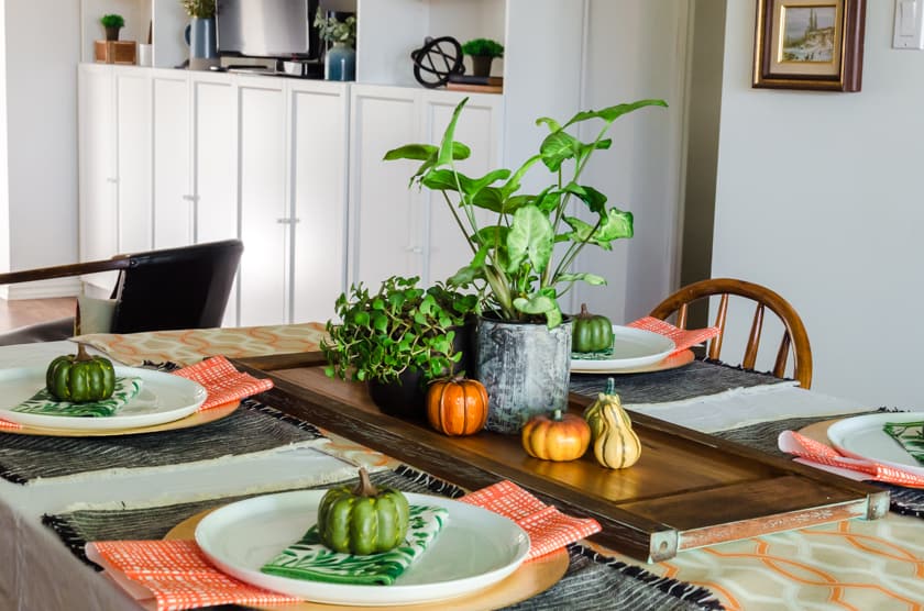 Table set in fall colors in a dining room with the open concept living room in the background