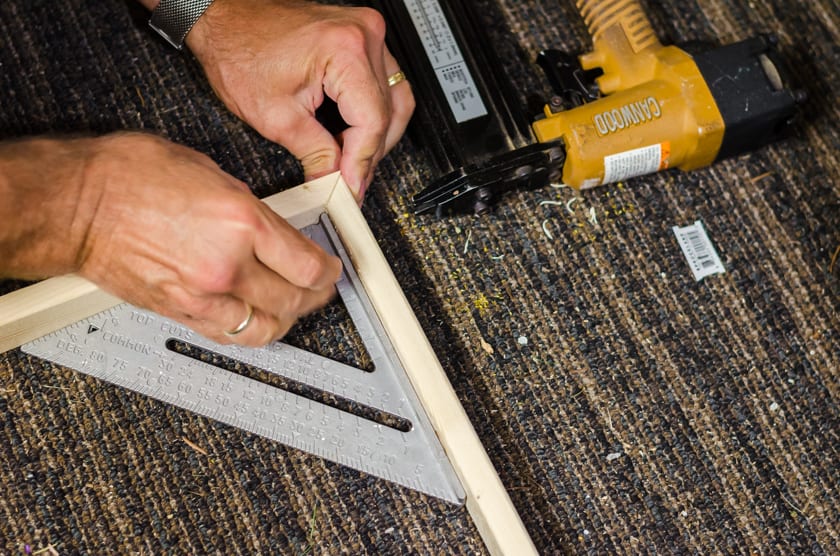 a brad nail gun being used to attach the mitered corners of a floating frame.