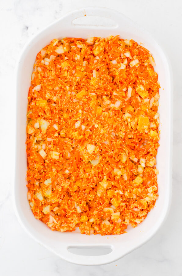 Shredded carrot casserole in a casserole dish ready to be baked.