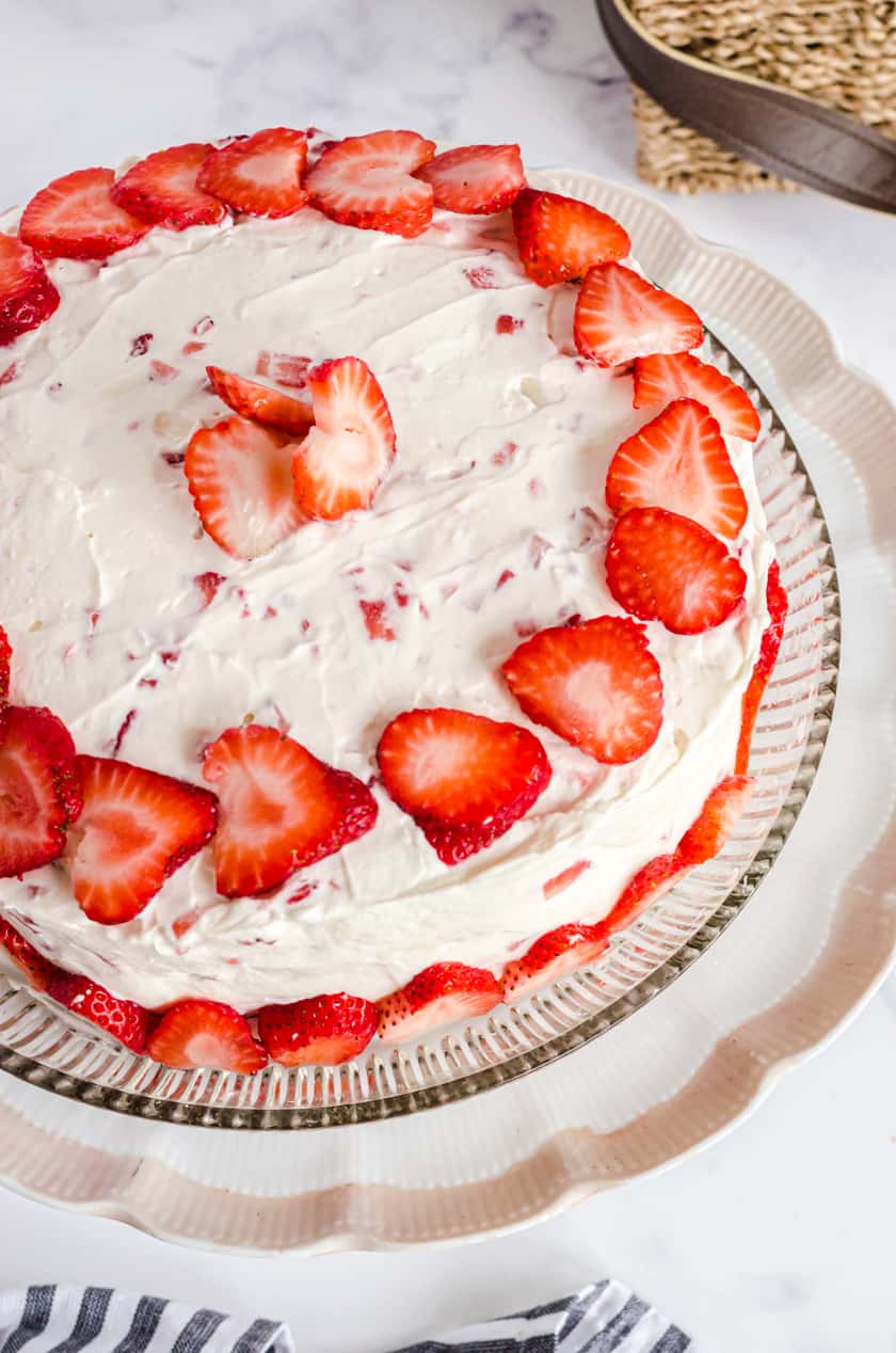 The top of a vanilla cake with fresh strawberry icing on a cake platter.