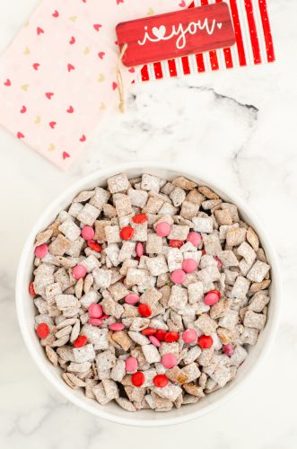 Finished bowl of puppy chow mix with pink and red candies for valentines day.
