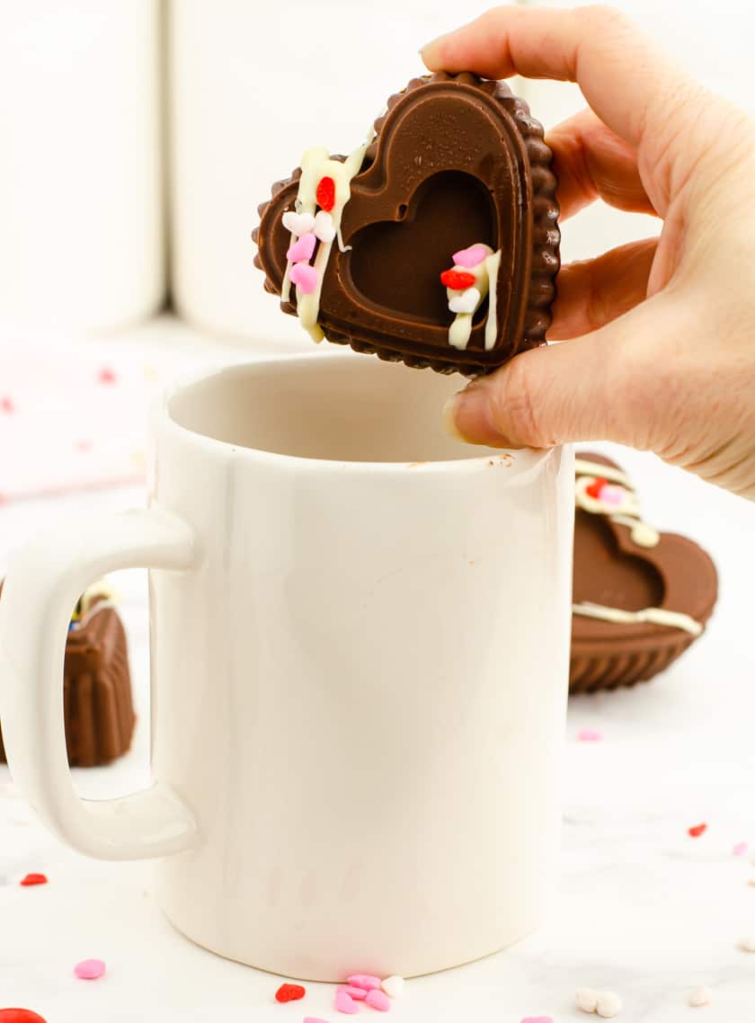 A valentine chocolate bomb being placed in a large mug