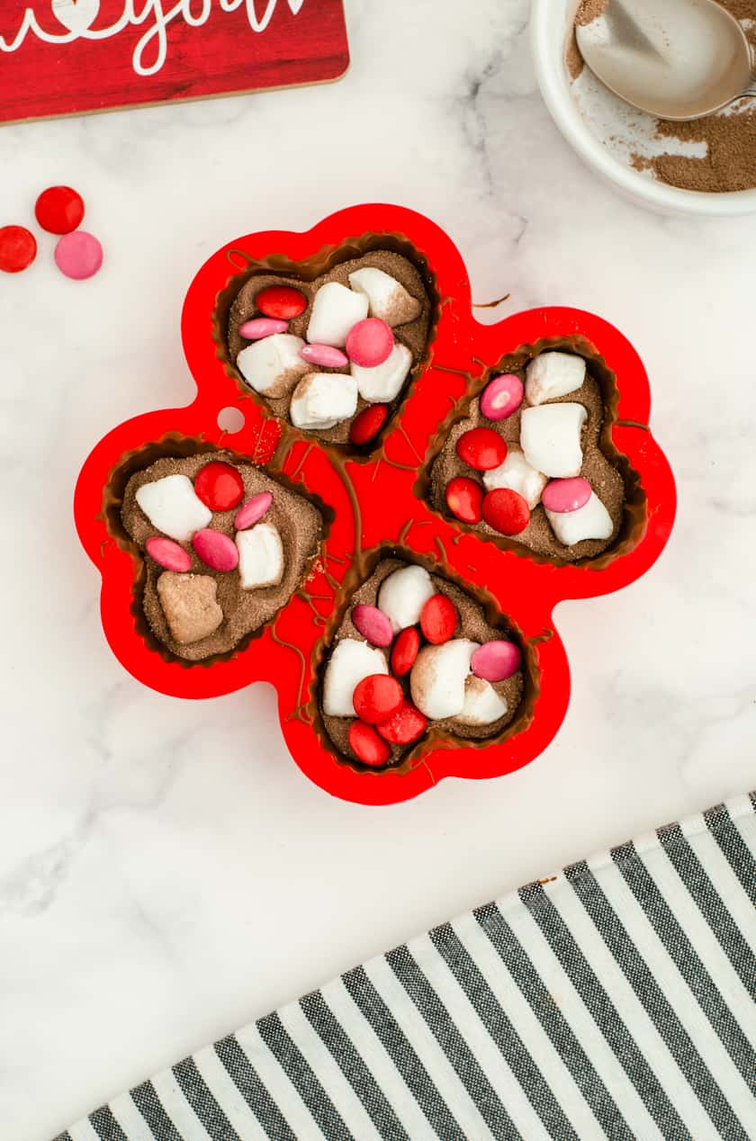 Valentine hot chocolate bombs in heart shaped molds with red and pink m& ms and marshmallows