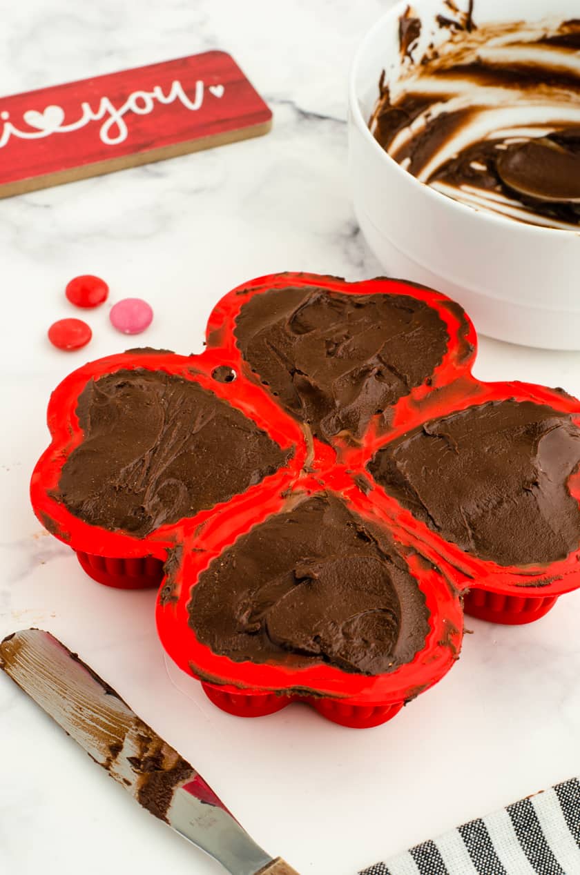 heart shaped hot chocolate bombs in heart shaped molds with the hot chocolate powder, m & ms, and marshmallows in the middle