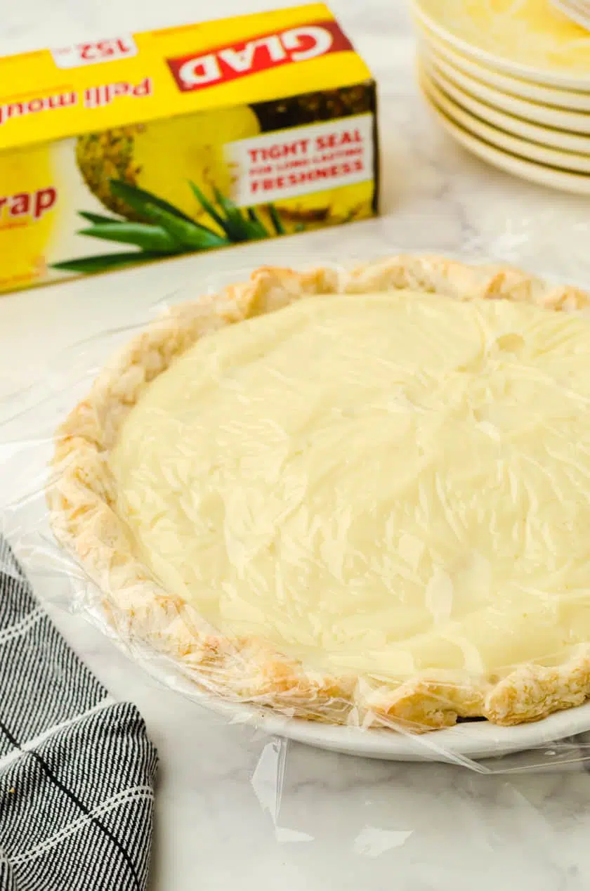 Banana Cream pie with pudding with plastic wrap covering it.