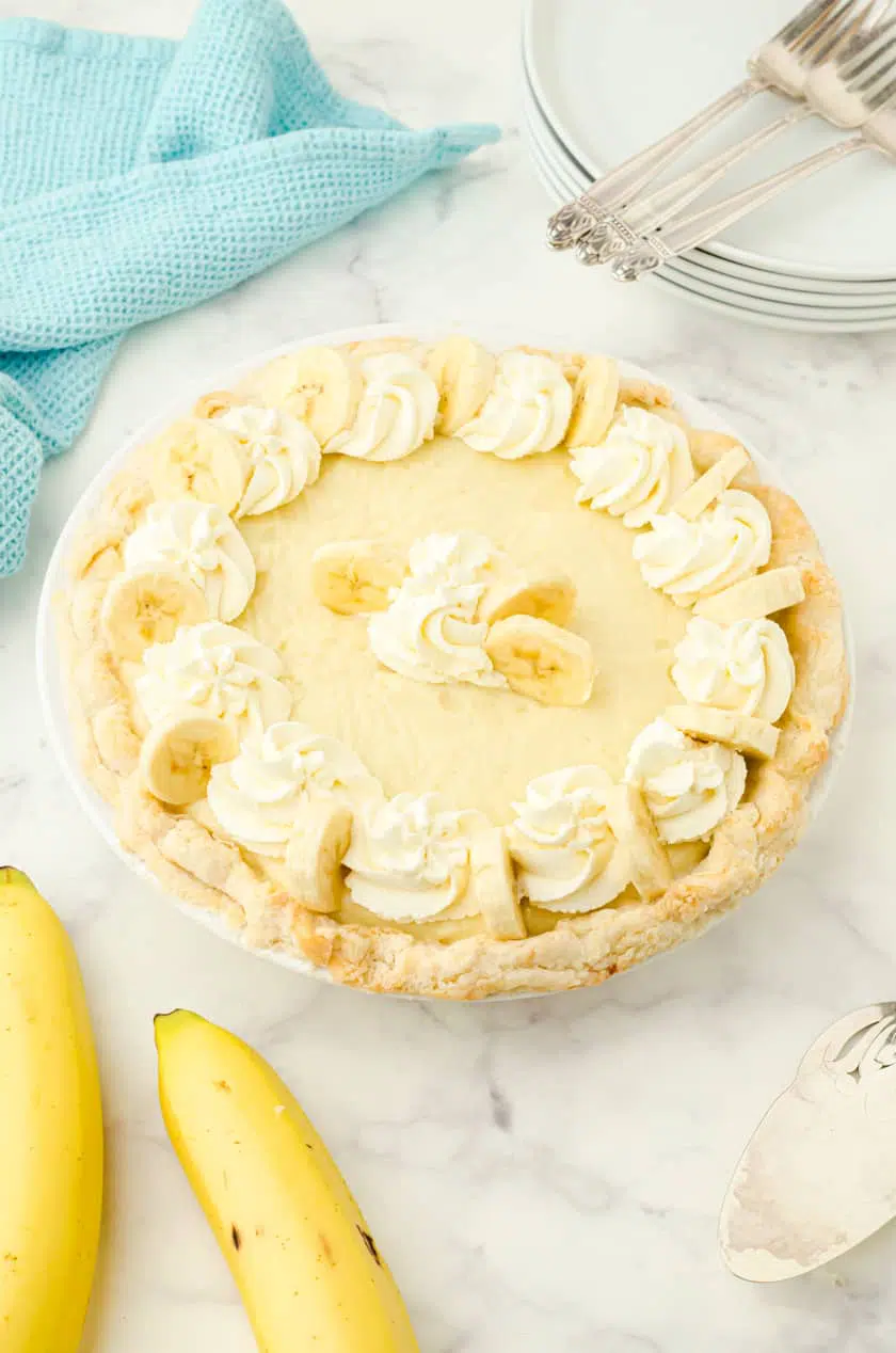 Whole banana cream pie with whipping cream and banana slices on the top