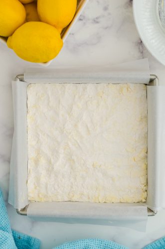 The shortbread crust for lemon bars pressed into a parchment lined 8 x 8 inch pan