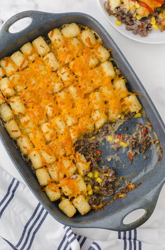 A pan of tater tot casserole recipe with a scoop of it missing.