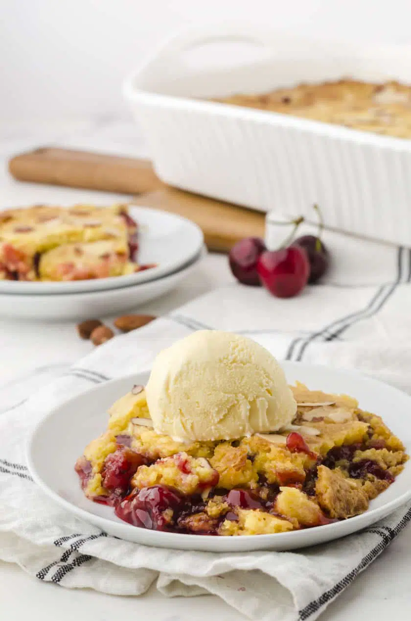 Cherry dump cake on a plate with a scoop of vanilla ice cream on the top
