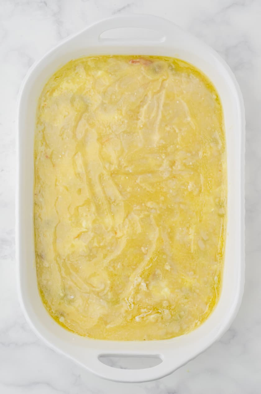 Melted butter spread over cake mix for a cherry dump cake recipe.
