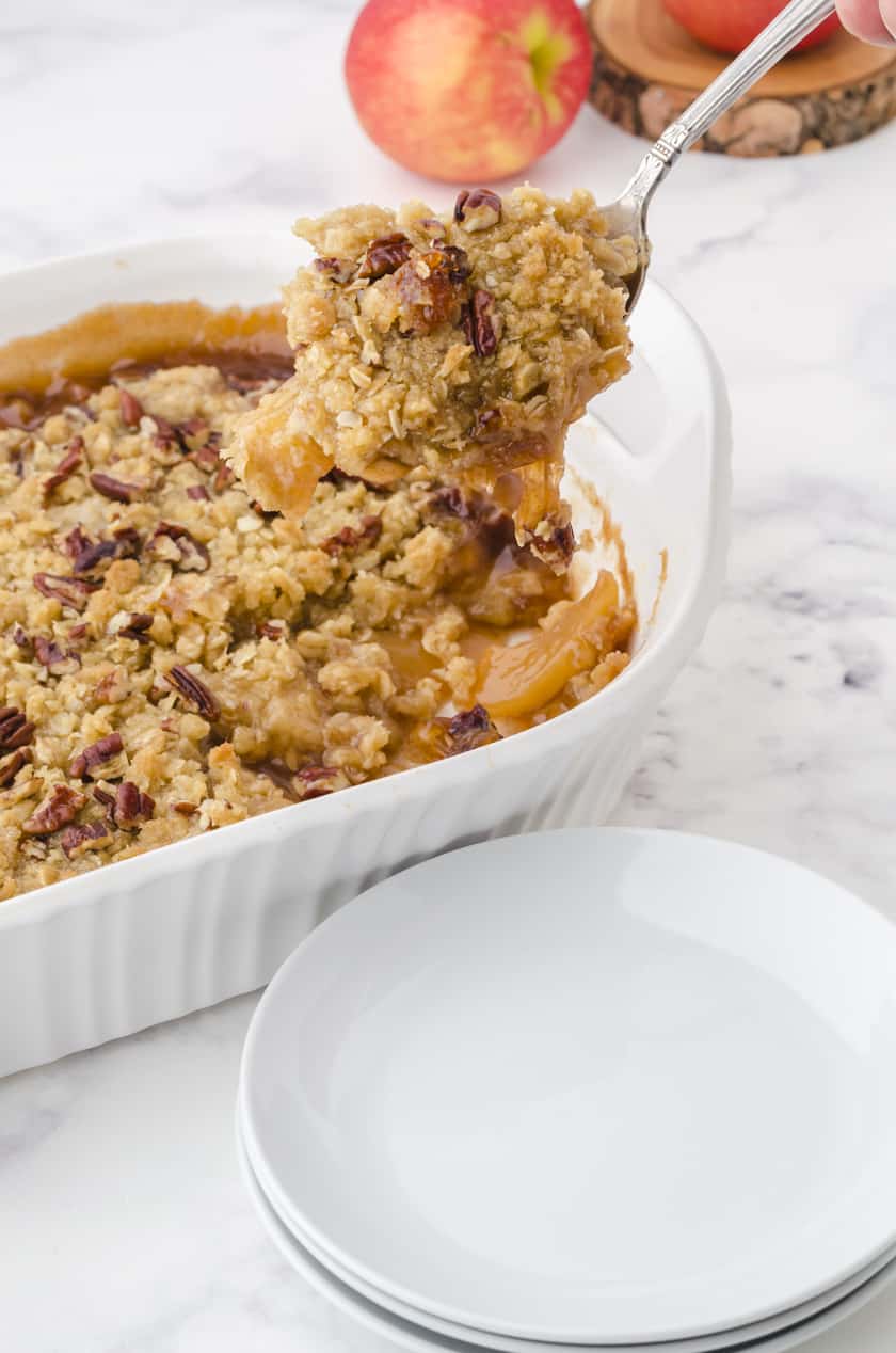 Large serving spoon dishing out apple crisp.