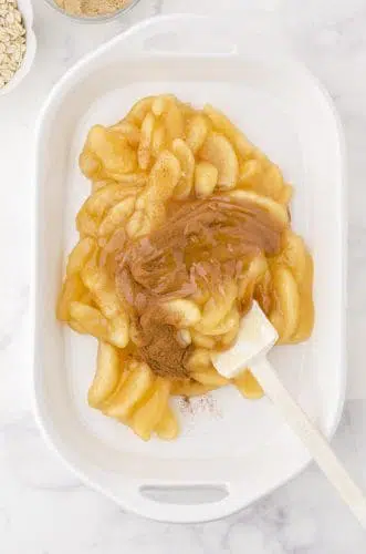 apple pie filling and cinnamon being stirred together as the base for apple crisp with pie filling