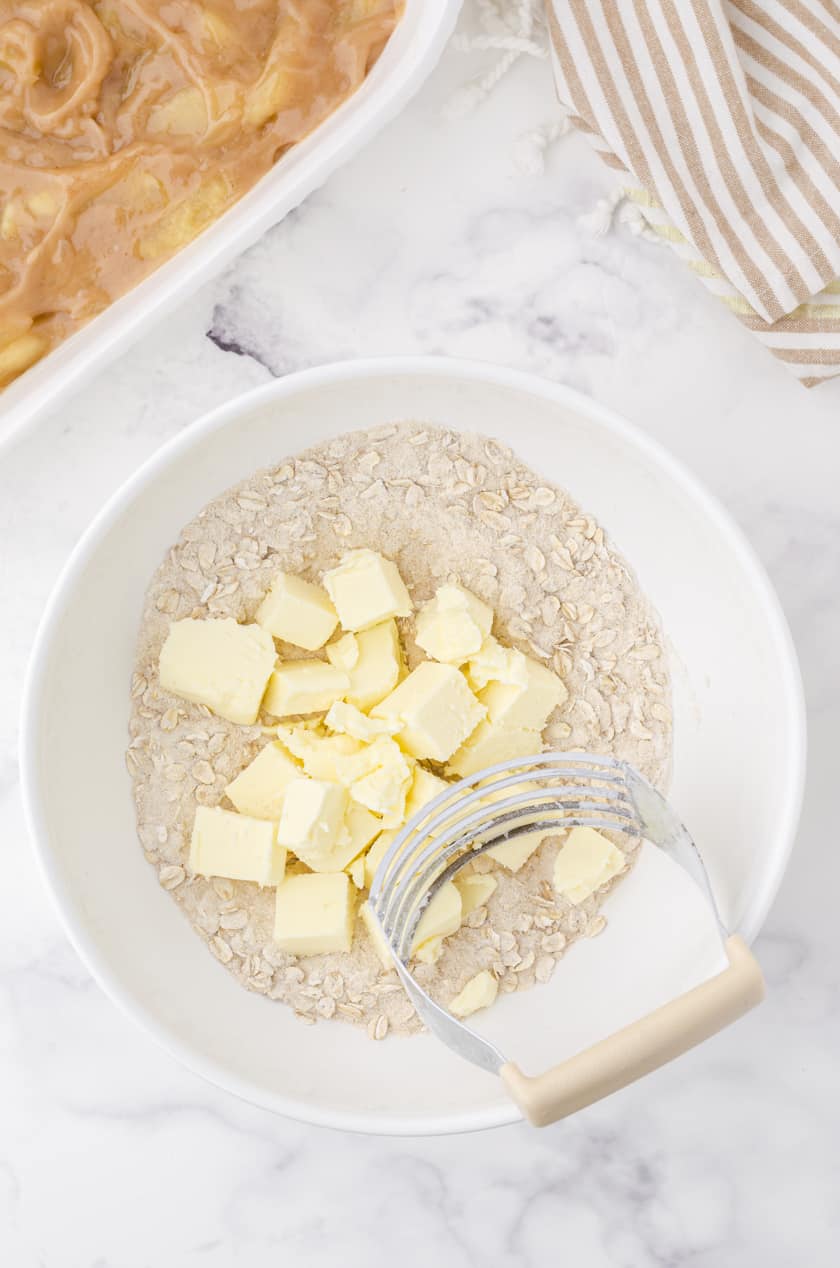 Crisp topping mixture with butter cubes and a pastry blender in a bowl.
