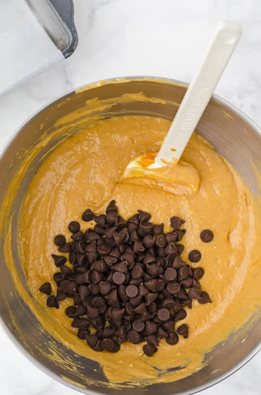 Chocolate chips being stirred into pumpkin bread batter