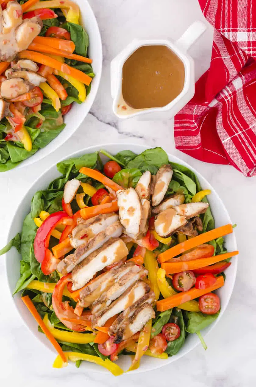 Grilled chicken salad with peanut chili sauce drizzled over the top