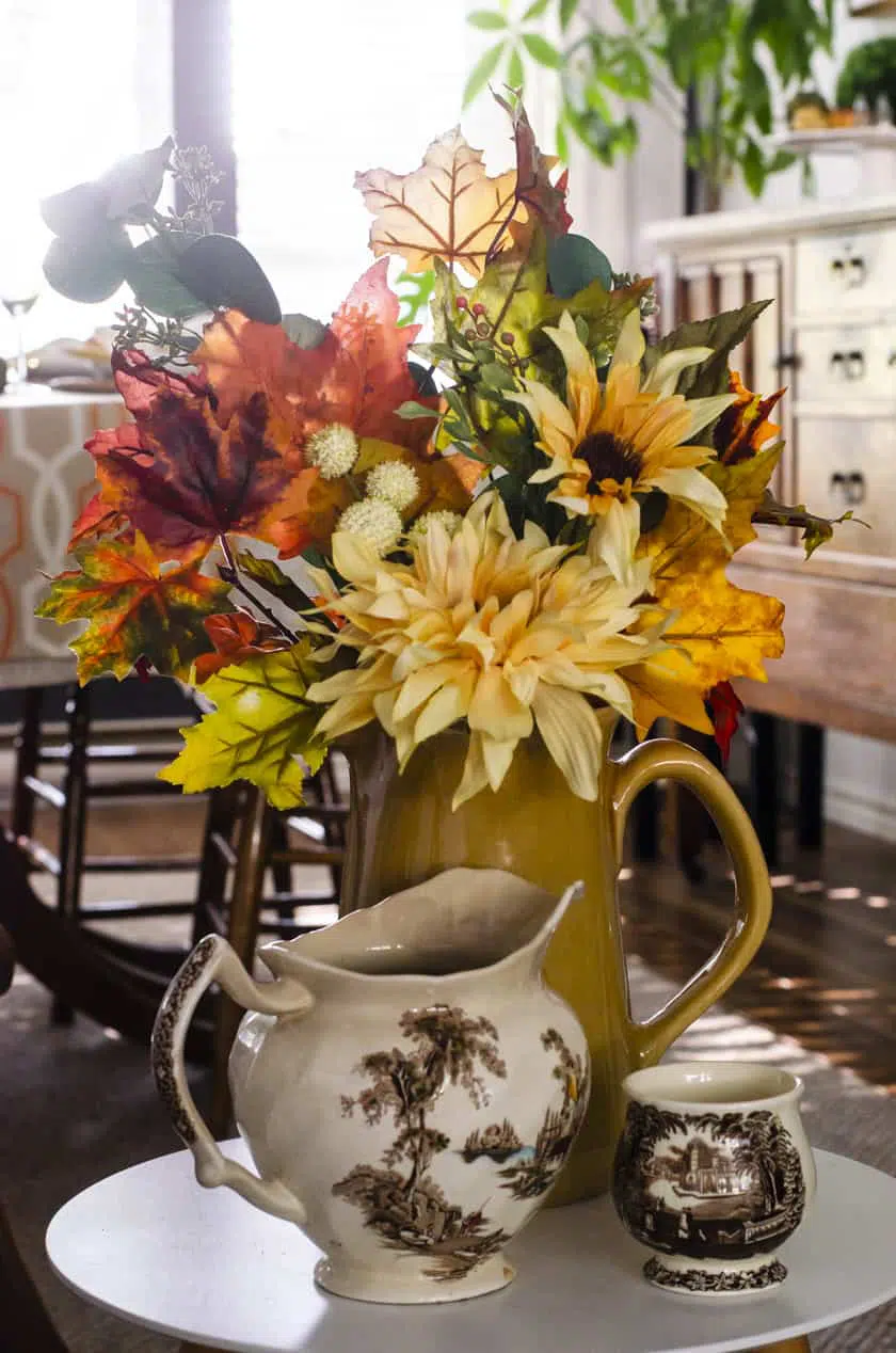 Fall artificial floral arrangement in a sunflower yellow stoneware pitcher.