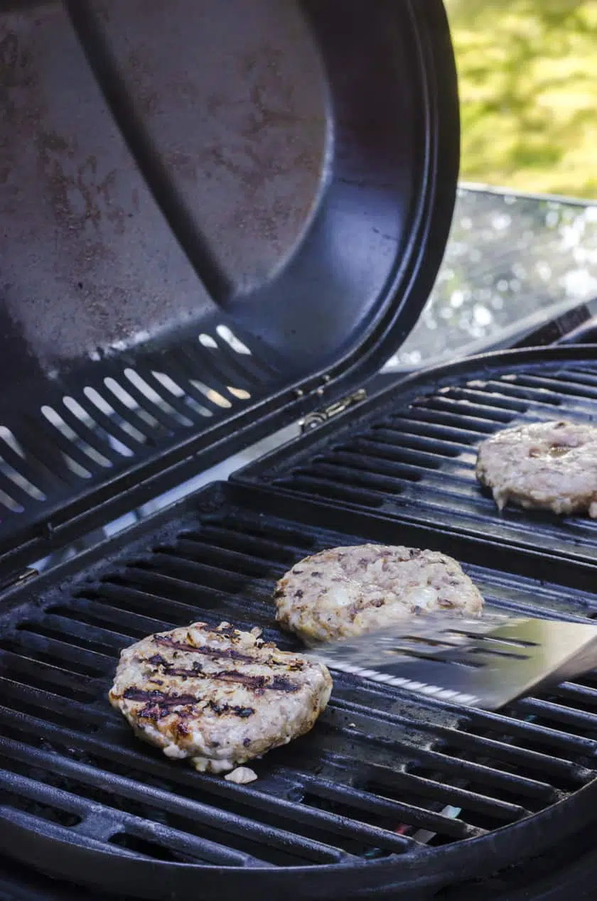 A grilled turkey burger patty on a barbecue grate with the grate marks showing on the top.