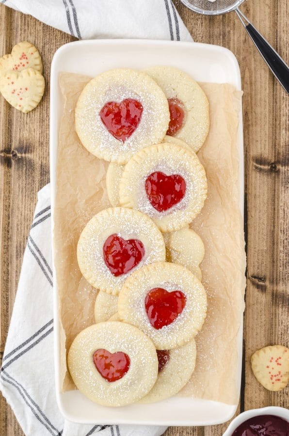 Jam Sandwich Cookies made with premade sugar cookie dough on a platter with red jam in heart cut outs.
