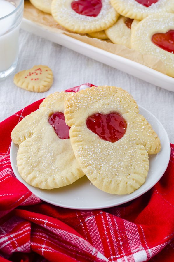 Jam filled sandwich cookies cut in the shape of mittens with a heart cut out in the middle filled with strawberry jam.