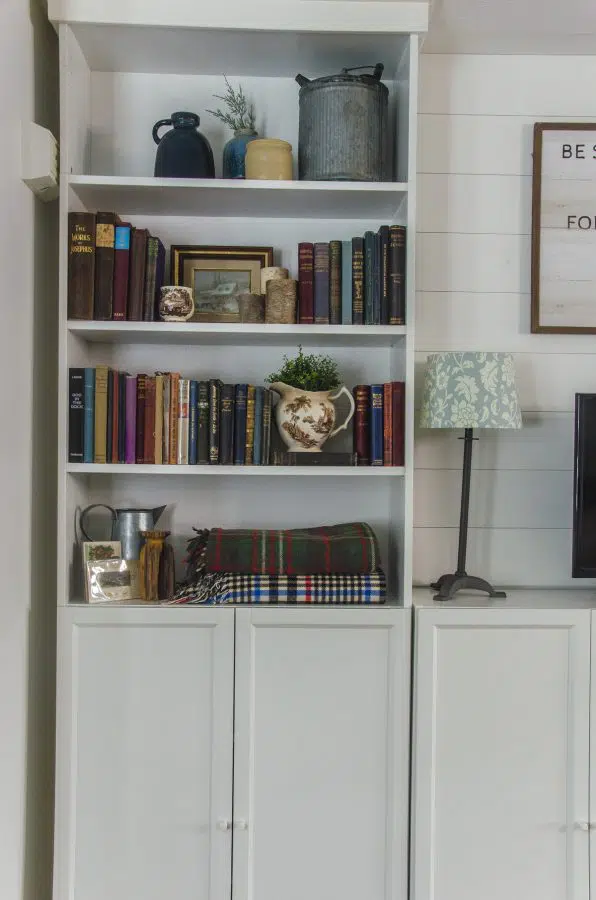 An Ikea Billy Bookcase decorated with the cottagecore aesthetic - vintage books, stoneware, plants, and rustic items.