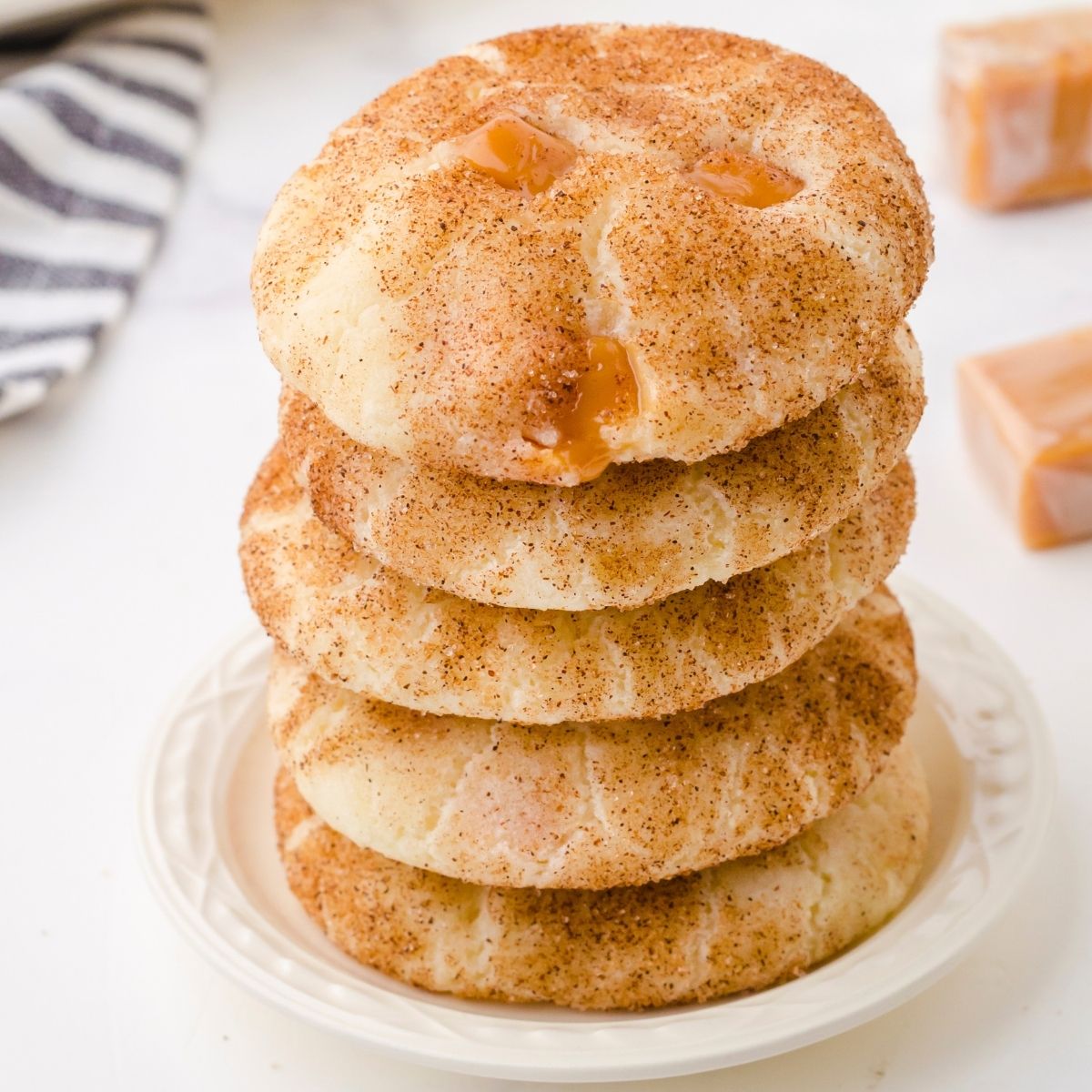 caramel snickerdoodle cookies stacked on a small white plate