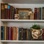 Livingroom bookshelves styled in the farmhouse cottagecore style with vintage books , stoneware, and plants