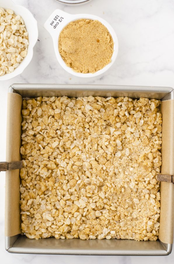 The Rice Krispies base pressed into the bottom of a parchment paper lined baking pan.